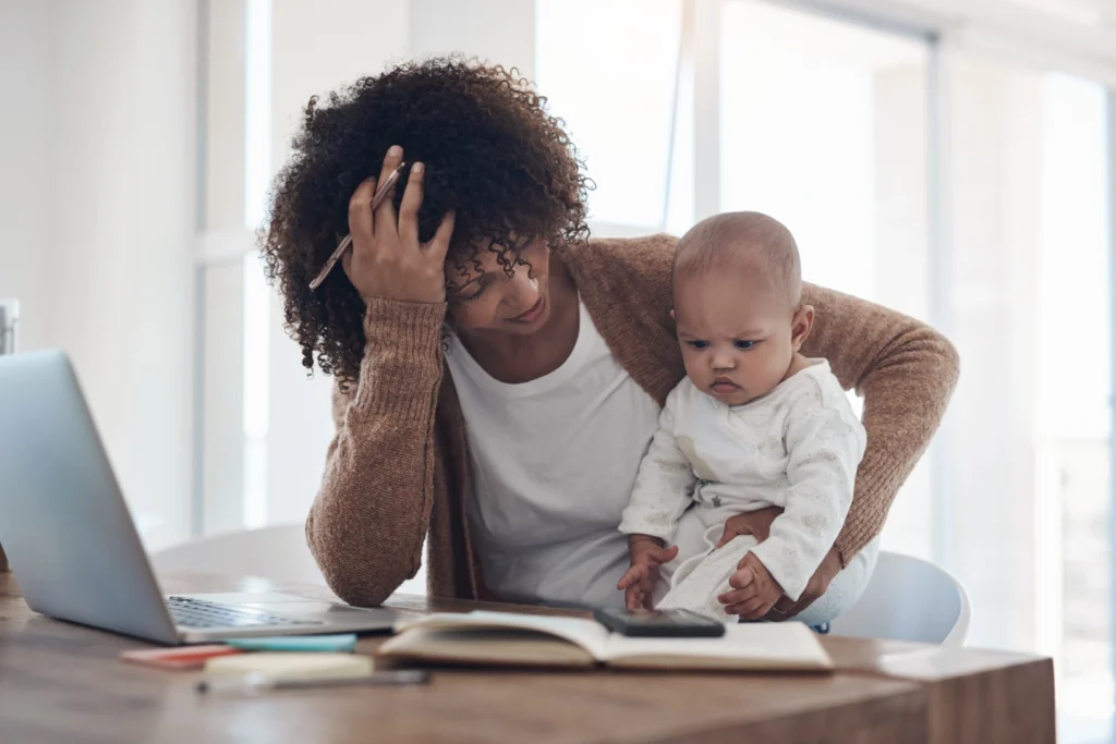 Tired mother holding baby while reading.