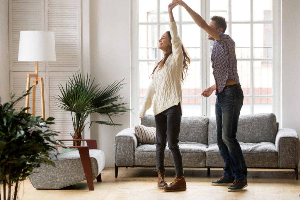 Couple dancing together joyfully in a cozy living room.
