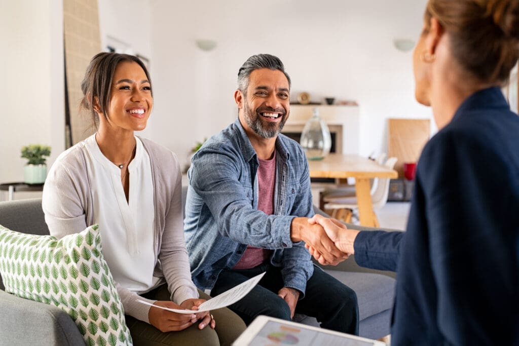 Couple smiling and shaking hands with a professional.