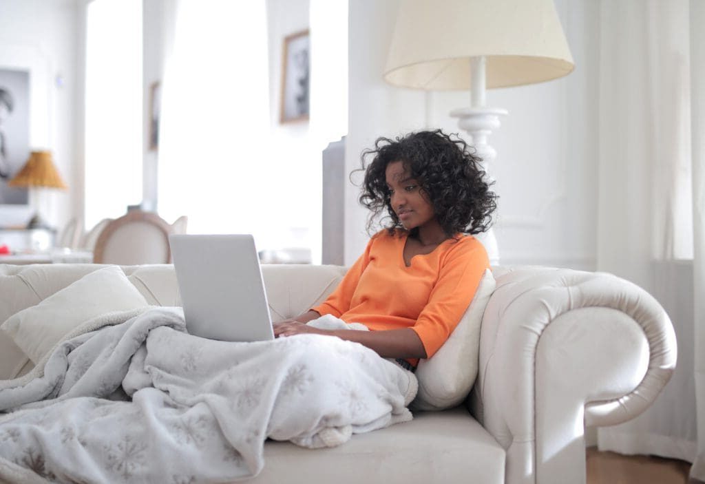 Woman relaxing on couch using a laptop.