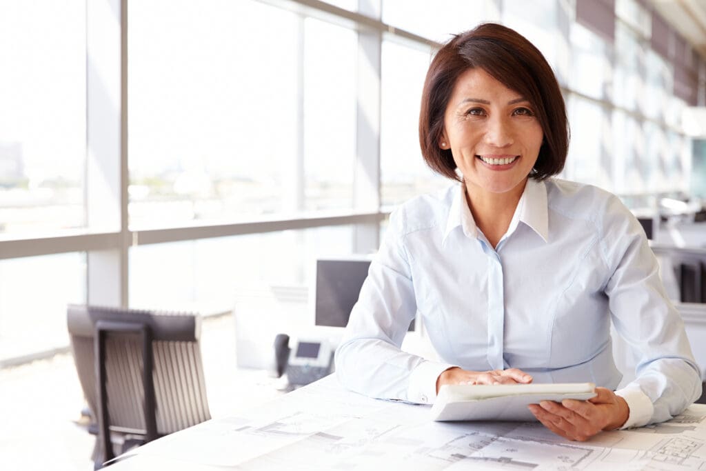 Smiling woman holding a tablet in a bright office.