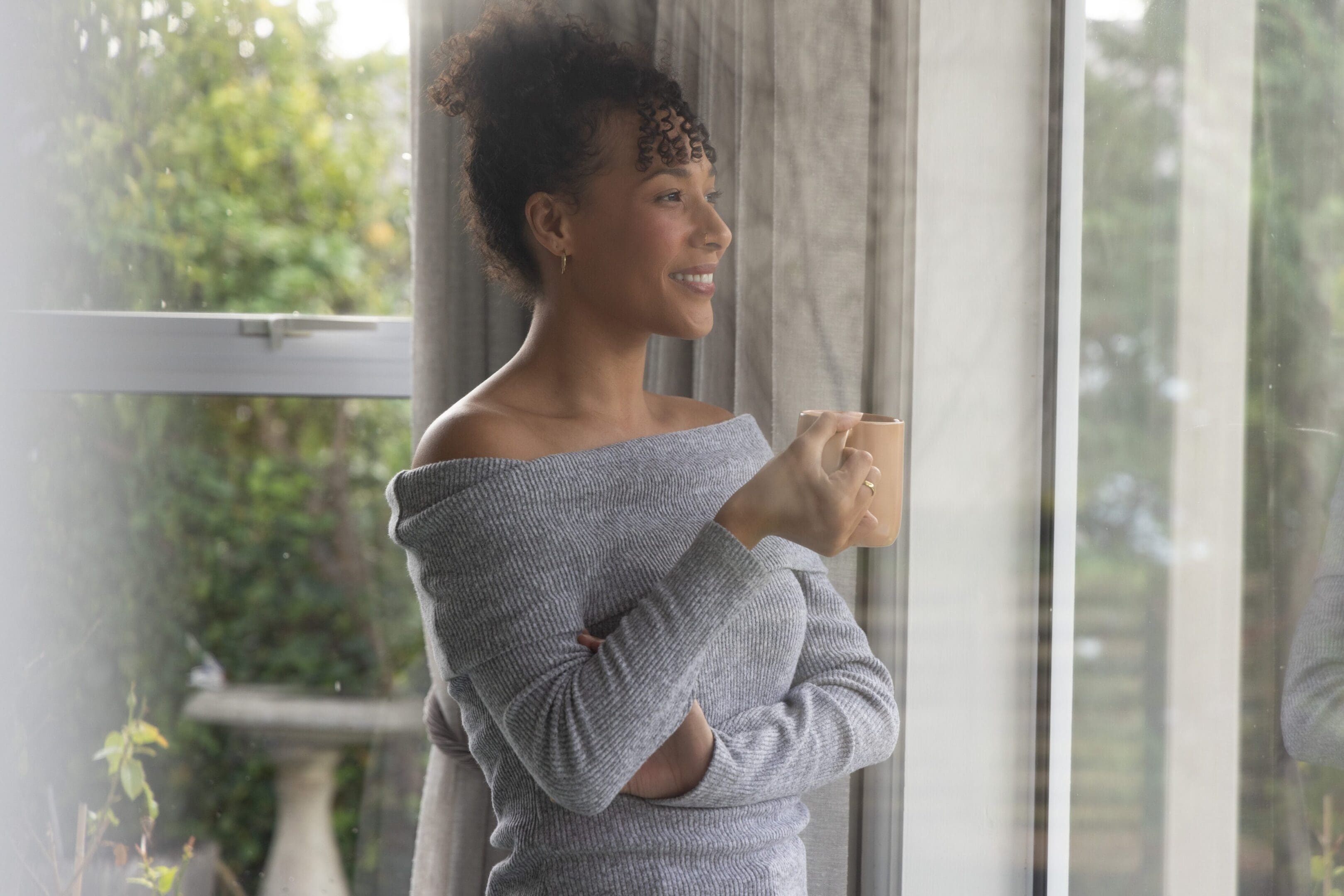 Woman looking out of window with coffee cup