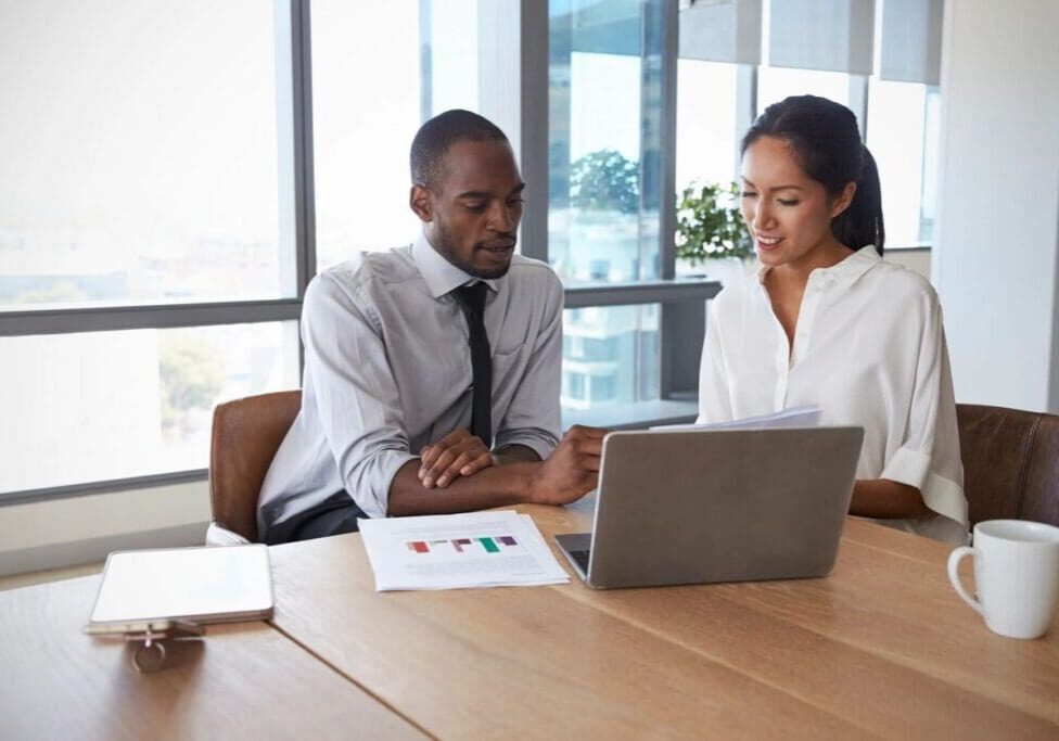 Two professionals discussing data in an office meeting.
